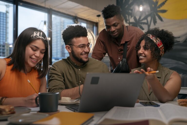 Equipe conversando e sorrindo ao redor de um notebook